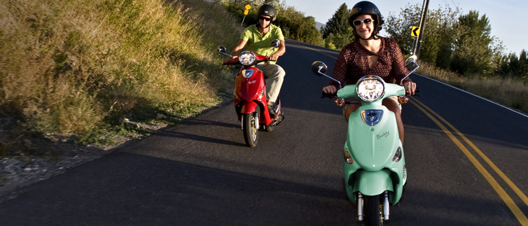 Two people riding scooters