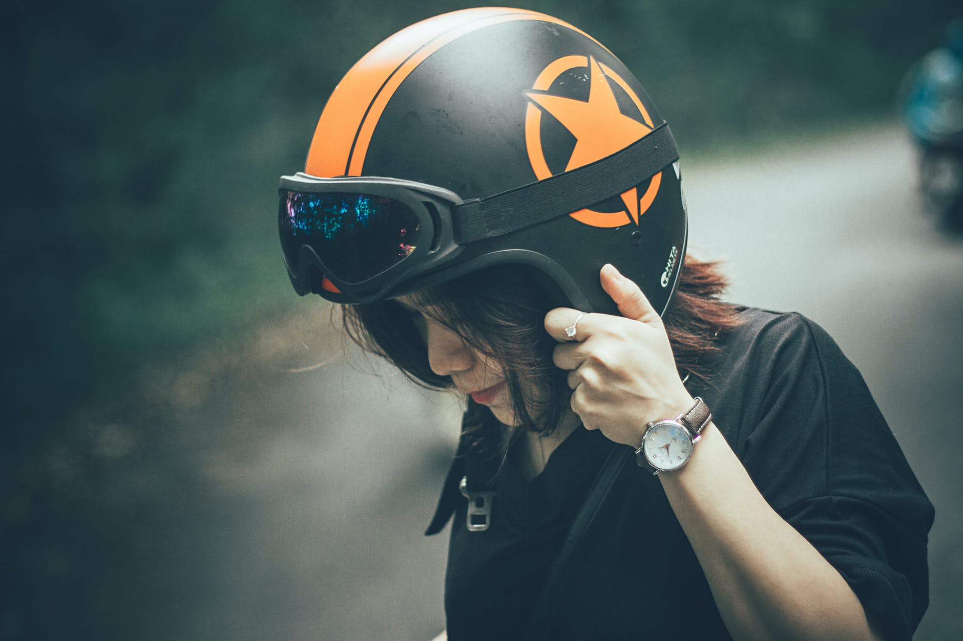 woman wearing black shirt and black and orange half face motorcycle helmet