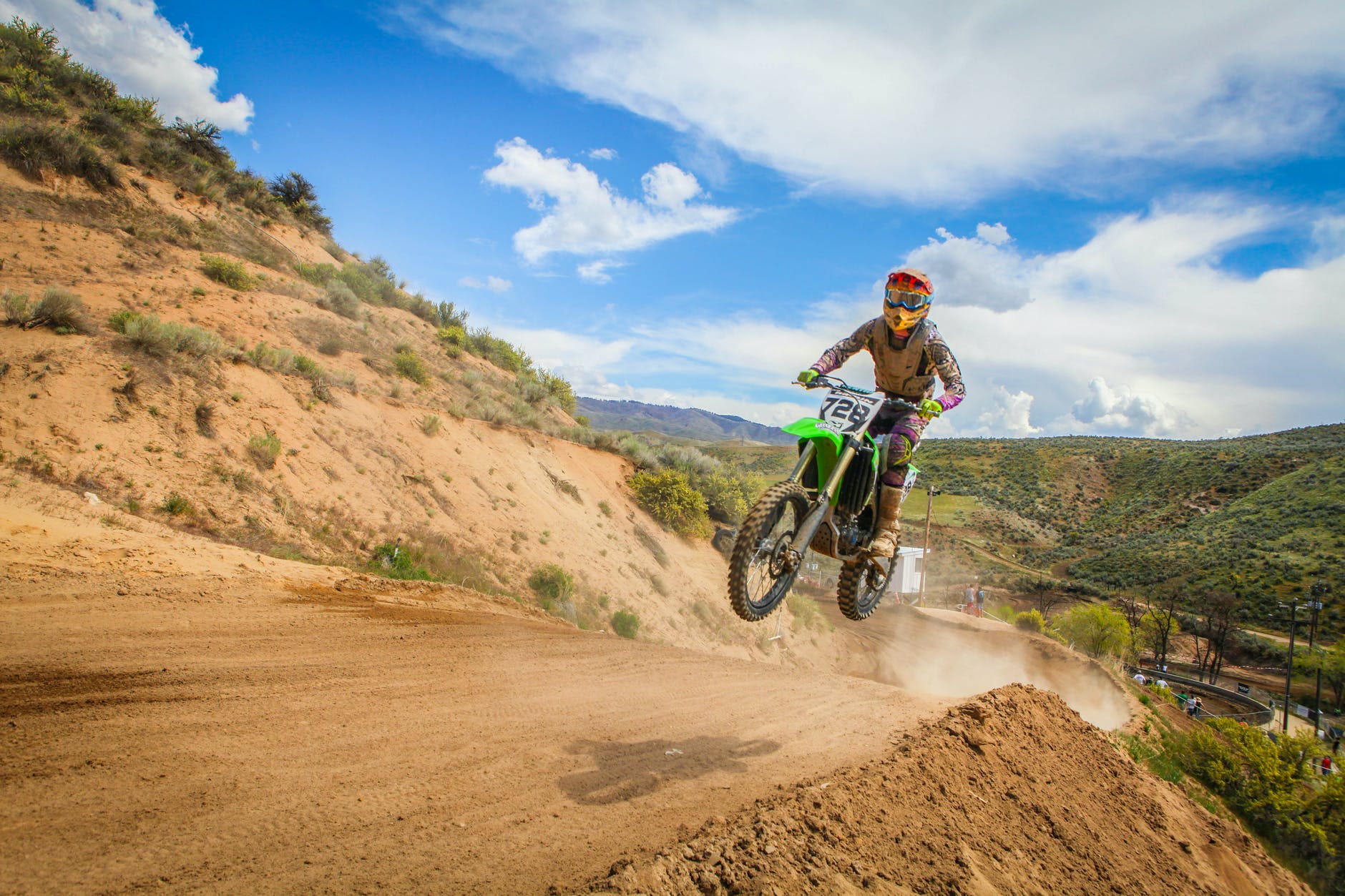 human riding dirt bike motorcycle and jumping under blue sky during daytime. 