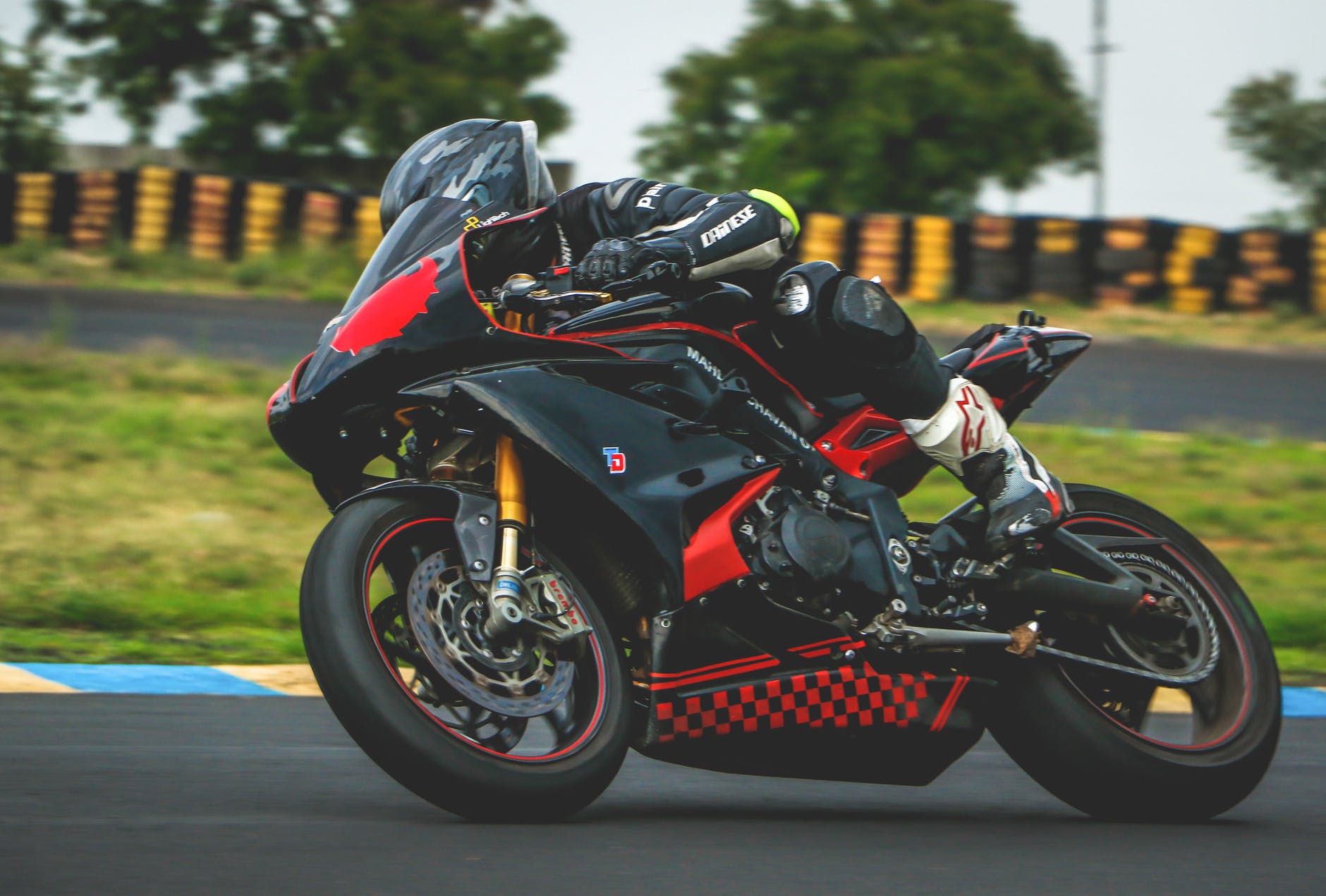 man with black alpinestar racing suit riding black and red sports bike. A sportbike rider wearing gear.