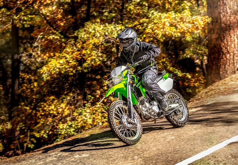 A rider wearing a dual sport helmet on a Kawasaki KLX 300