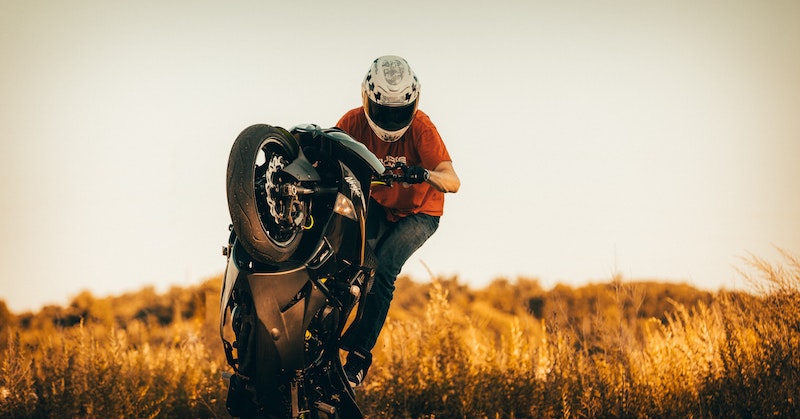 Motorcycle wheelies on a sportbike with a rider wearing a helmet and gloves. 