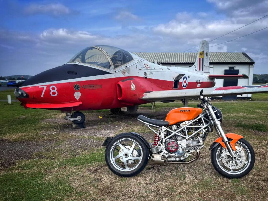 Custom Ducati Multistrada cafe racer parked in front of a jet.