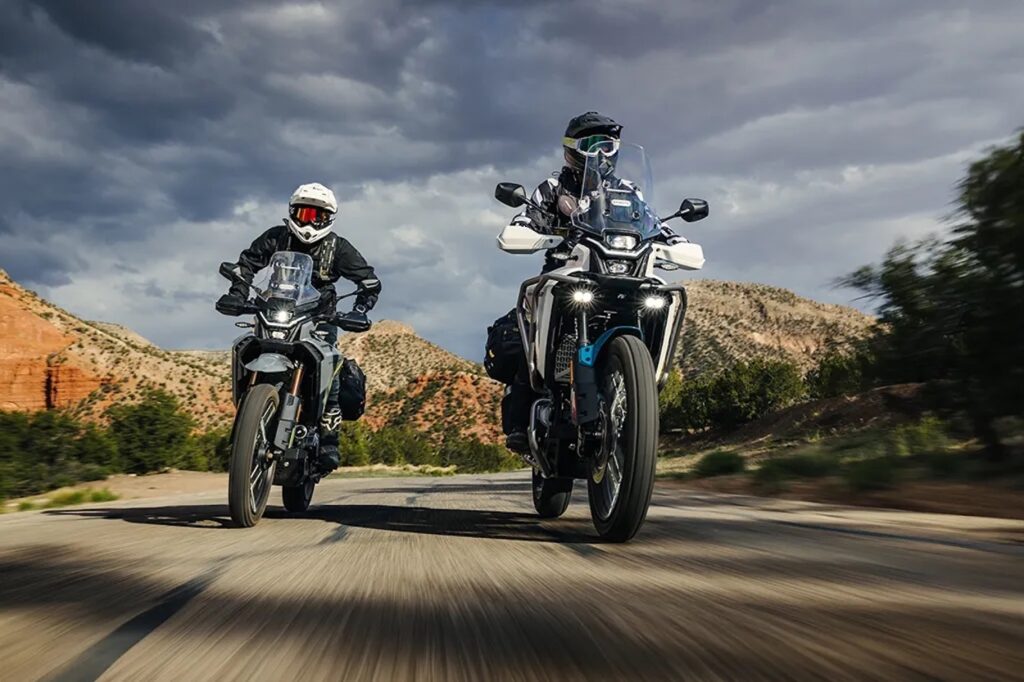 Two CFMOTO Ibex 450 riding on a paved road next to each other. 