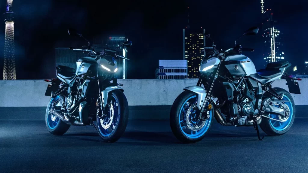 Two 2025 Yamaha MT-07 motorcycles parked in a parking garage at night in the middle of a city.