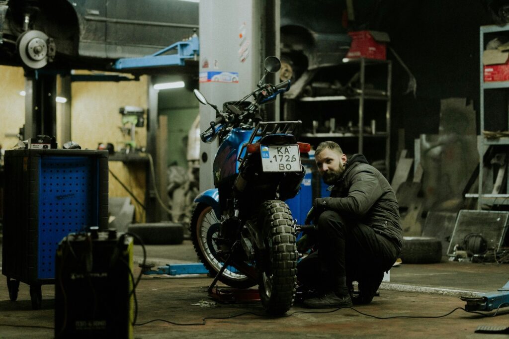 A mechanic doing maintenance on a motorcycle in a shop.