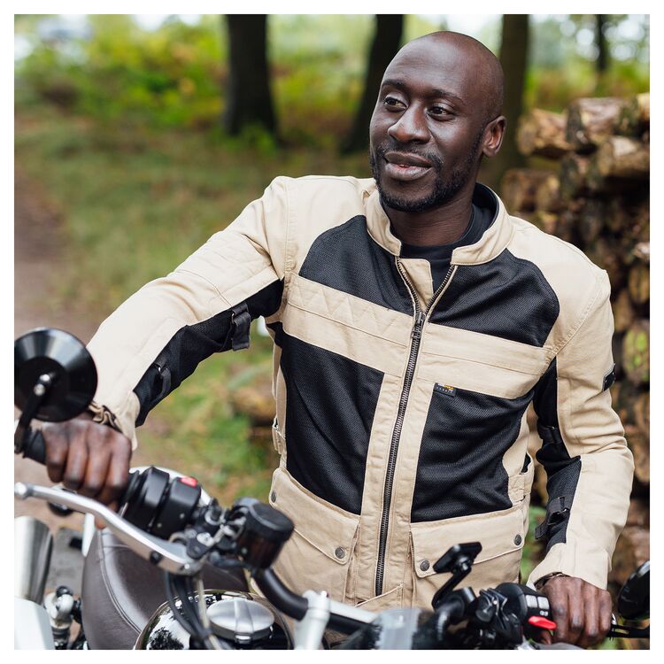A motorcyclist wearing the Merlin Mahala D3O Raid Jacket in the sand color.