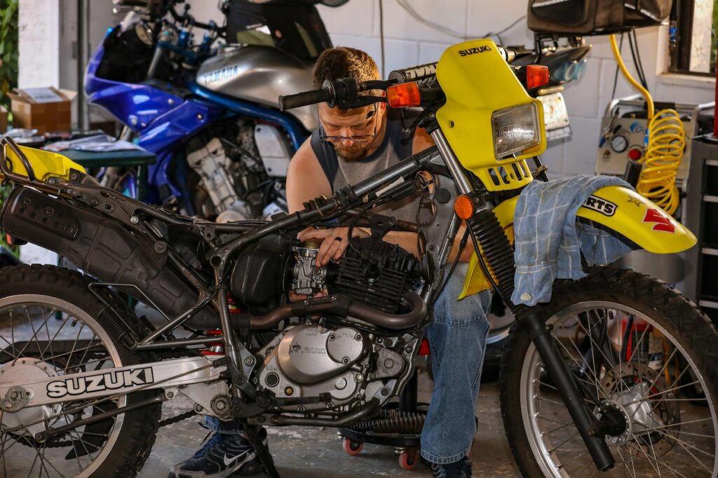 A man doing maintenance on a dual sport motorcycle. 