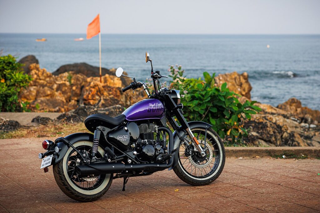 a Royal Enfield Goan Classic 350 parked on a sidewalk near rocks and water