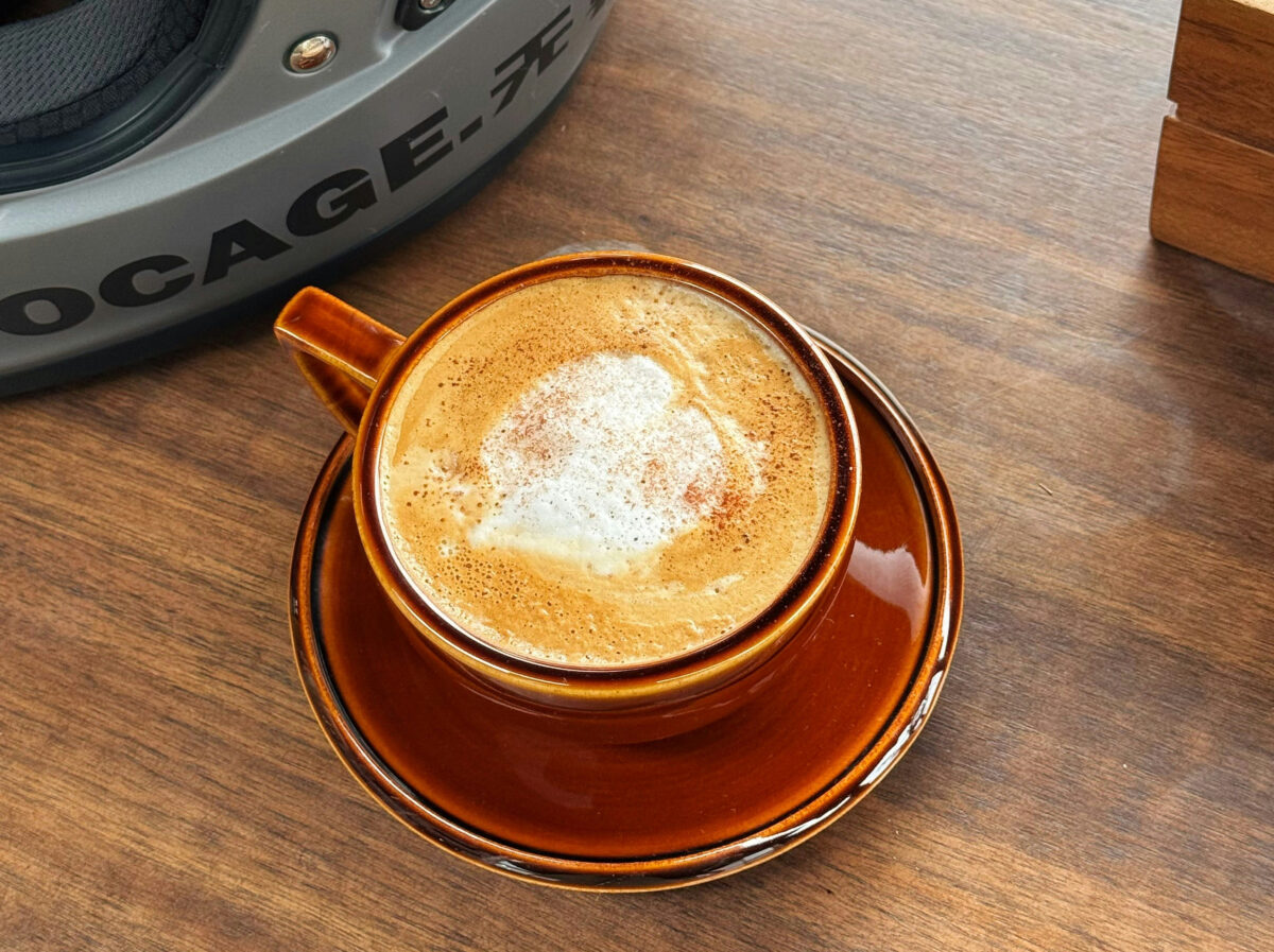 Coffee and a motorcycle helmet next to each other on a table.