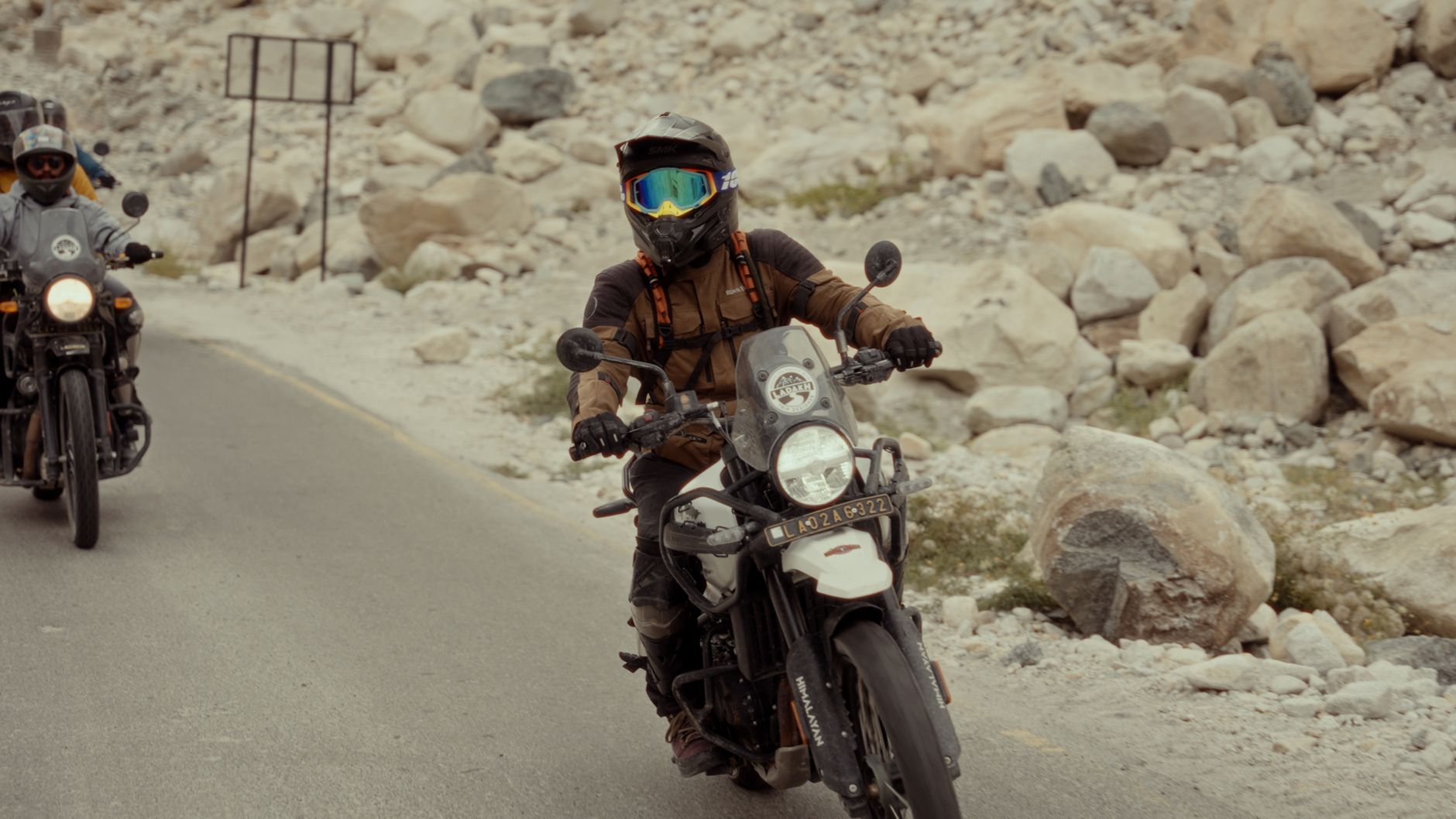 Motorcyclists in protective gear navigating a rocky road on their adventure.