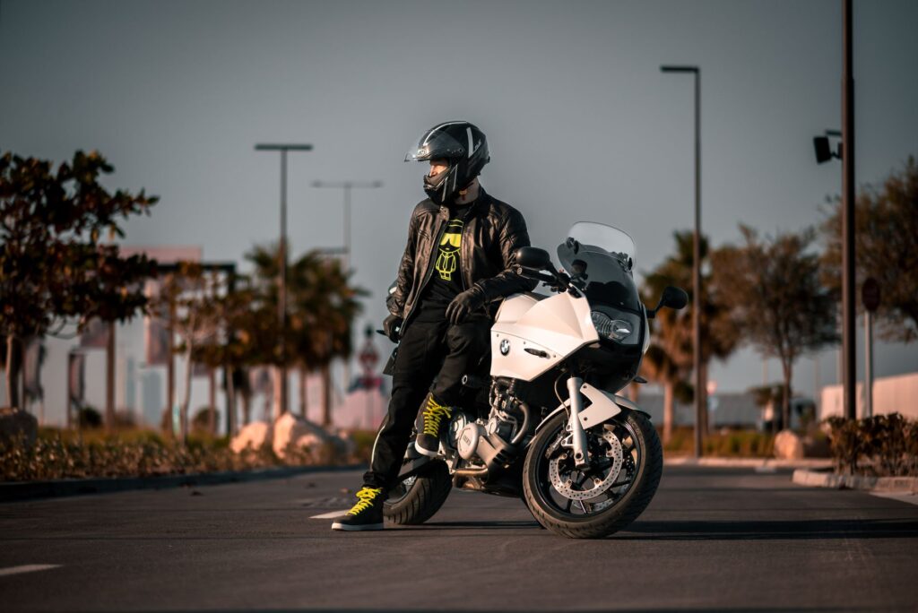 Rider in black gear stands with a BMW motorcycle during a sunny day ride.