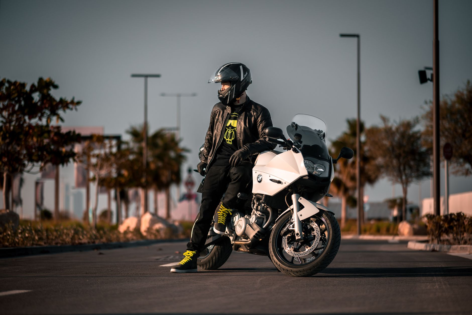 Rider in black gear stands with a BMW motorcycle during a sunny day ride.